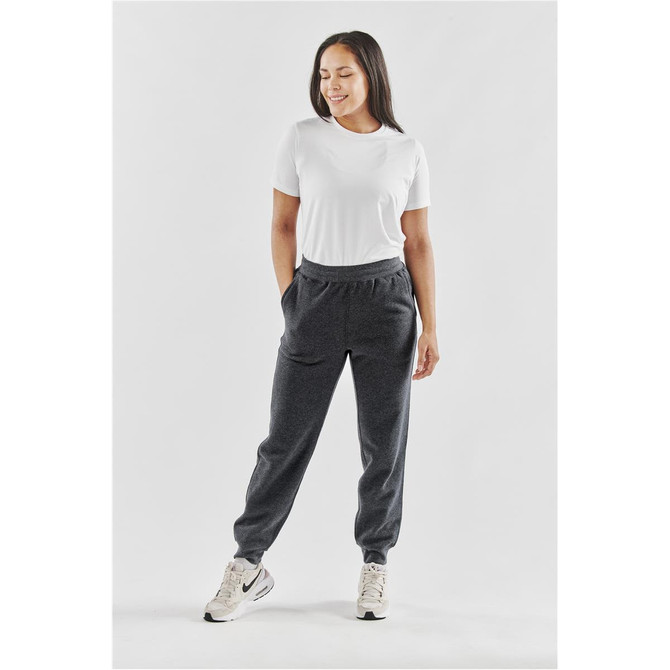 A woman stands wearing grey Monashee fleece joggers and a white t-shirt, featuring pockets and a casual fit.