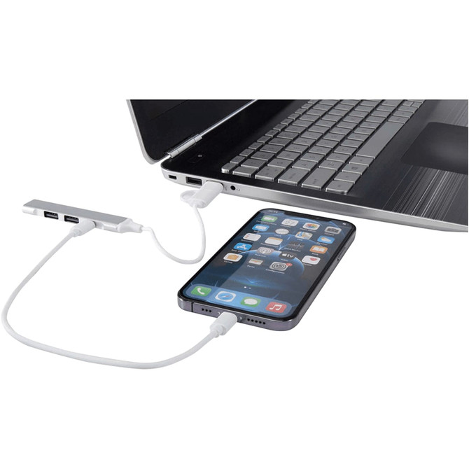 A 4-port USB hub in silver connects to a laptop with a phone attached, featuring USB-A and Type-C inputs.