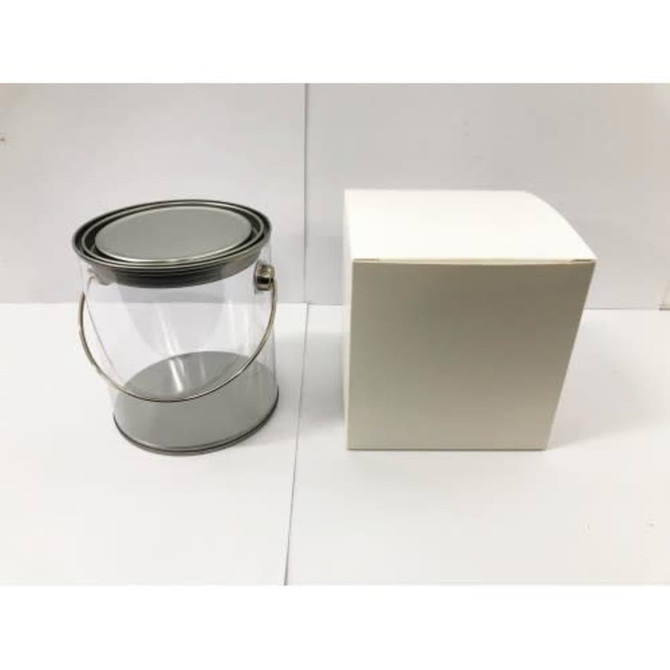 A clear PVC bucket with a metal handle beside a plain white box.