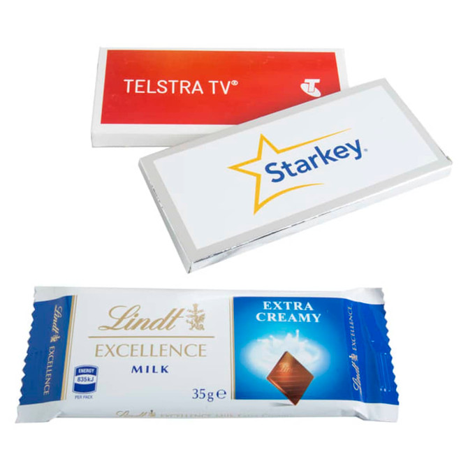 A milk chocolate bar with white and silver packaging, featuring a logo and a bigger sticker design.