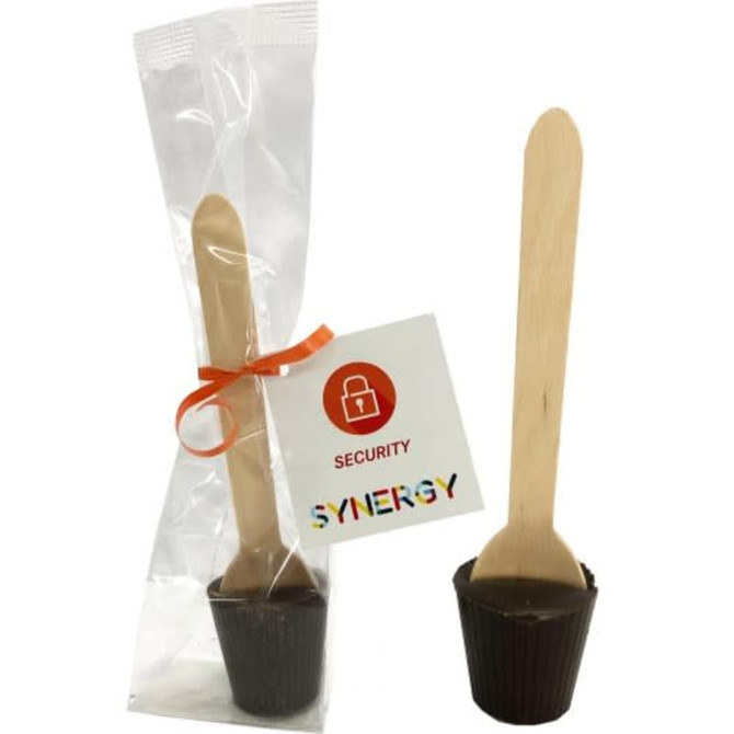 A chocolate spoon in a clear packet with an orange ribbon and a wooden stick, featuring a branded tag.