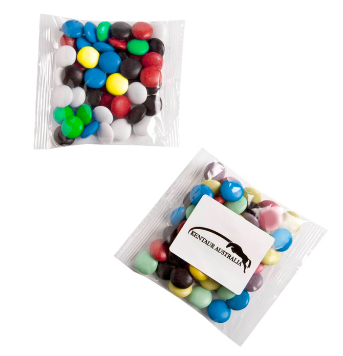 A clear bag contains an assortment of brightly coloured chocolate beans, featuring blue, green, red, yellow, white, and black.