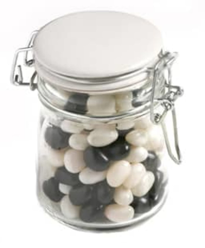 A glass clip lock jar filled with black and white jelly beans. The jar has a metal latch and a silver lid.