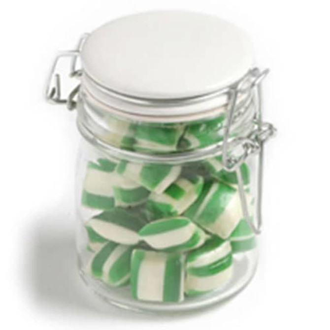 A glass clip lock jar filled with green and white humbug candies, featuring a metal lid.
