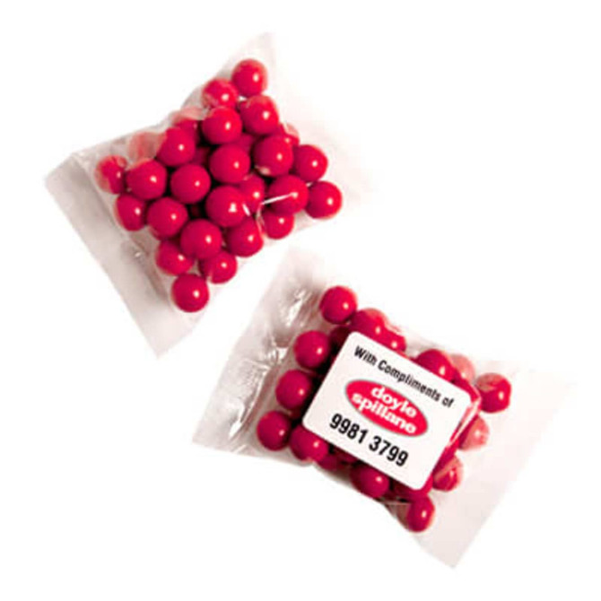 A transparent bag containing round, orange chocolate drops, resembling Jaffa lollies.