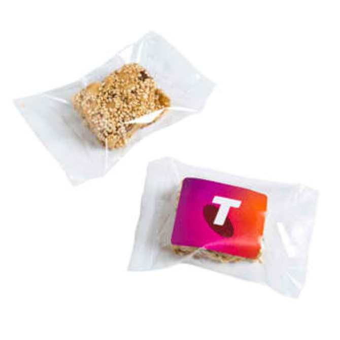 A sesame nut bar wrapped in clear packaging, featuring a golden-brown colour with a branded label.