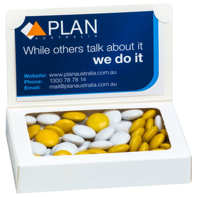 A white box containing yellow and white chocolate beans, featuring a logo on the lid.