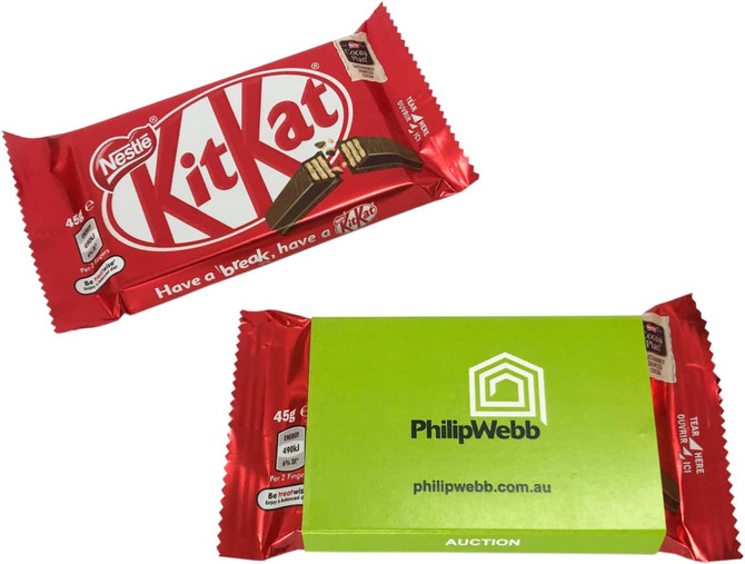 A red KitKat chocolate bar with a green sleeve packaging, featuring branding and product details.