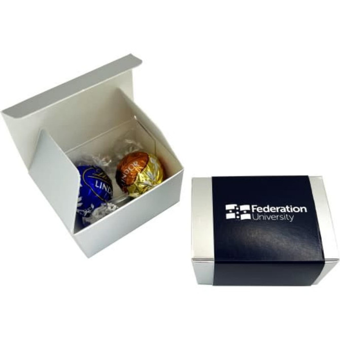 A two-pack box containing blue and gold chocolate balls, with a branded exterior.