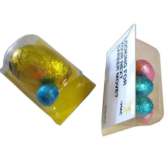 A transparent packaging filled with colourful Easter eggs: gold, blue, and pink, accompanied by a branded card.