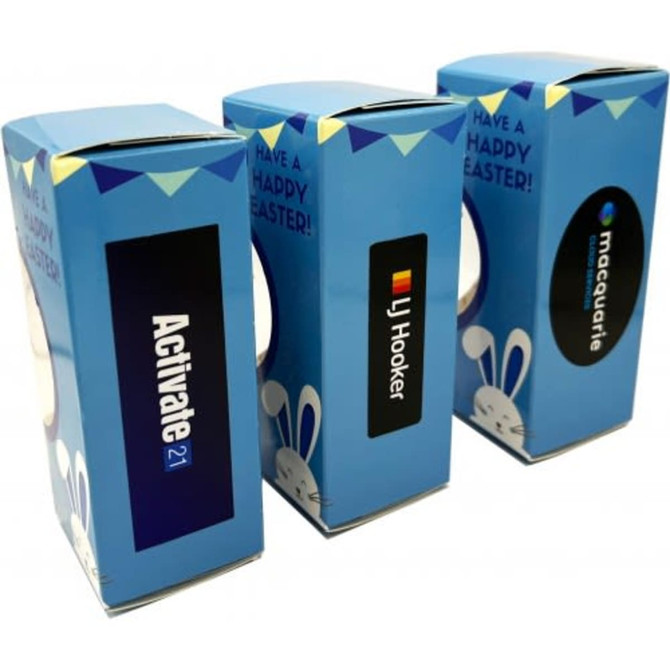 Three blue packaging boxes featuring Easter Bunny designs, intended for chocolates, each with different logos.