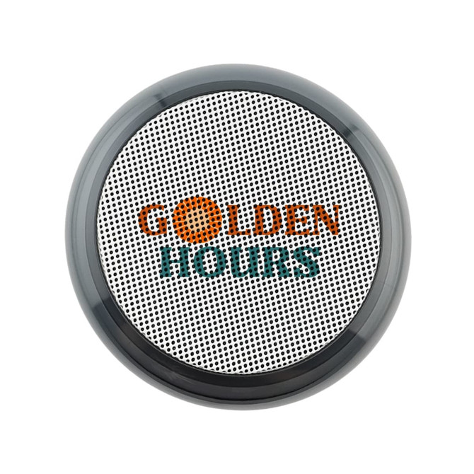 A round, black and silver speaker with a textured surface and a logo on the front.