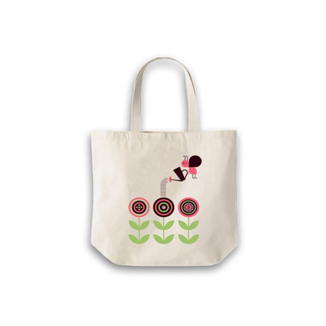 A calico bag with a short handle featuring a design of flowers and a character, in a light cream colour.