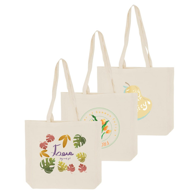Three cream-coloured calico bags with long handles and gussets, featuring various colourful designs and one logo.
