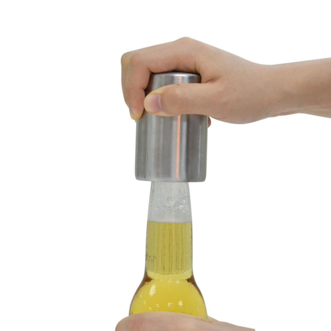 A drink bottle opener with a metallic finish, being used to open a beer bottle.