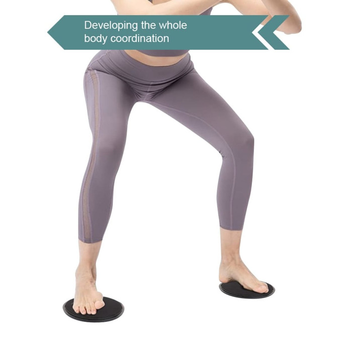 A pair of black yoga sliding disks on a white background, with a person performing a stance wearing grey leggings.