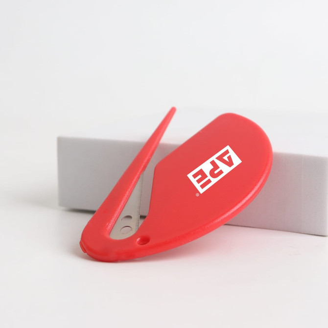 A red letter opener with a sleek design and a logo on the side, resting on a grey box.