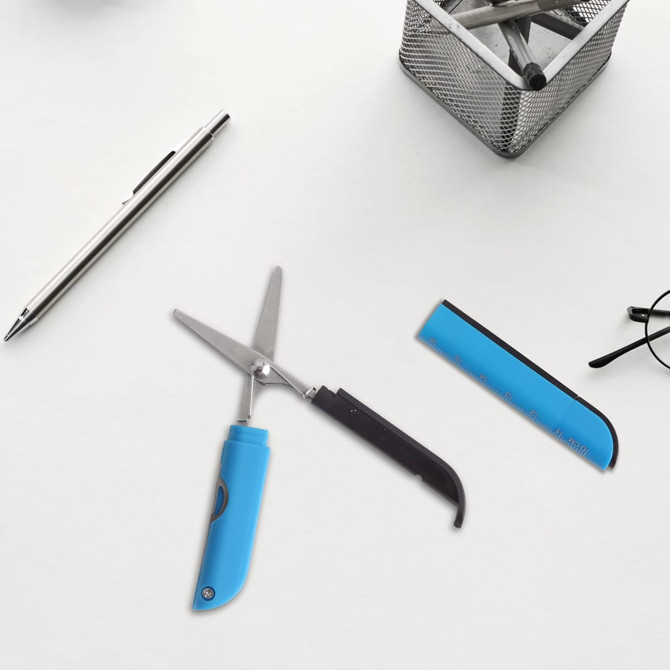 Multifunctional scissors with a blue handle, alongside a silver pen, a black ruler, and glasses on a light surface.