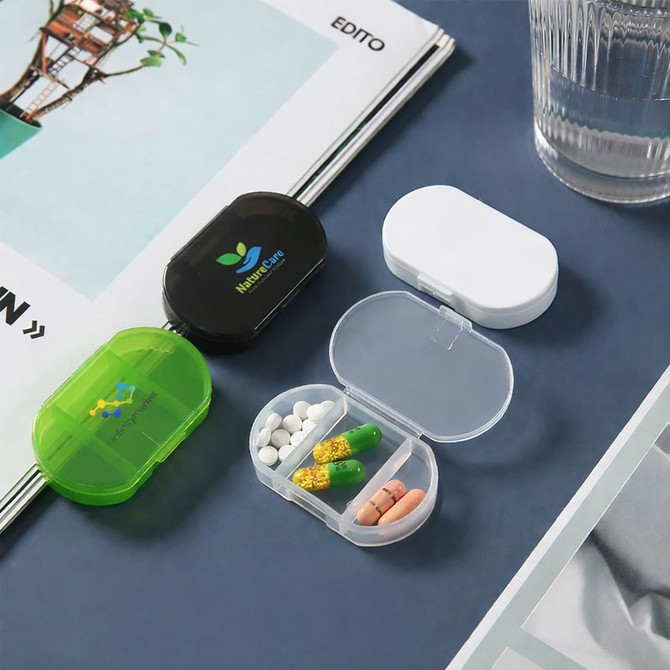 Three pill boxes in green, black, and white, displaying various pills inside a transparent compartment.