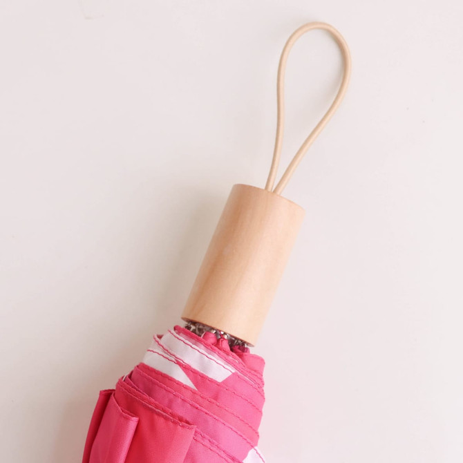 A lightweight pink umbrella with a wooden handle and a loop for hanging. It also features a logo.