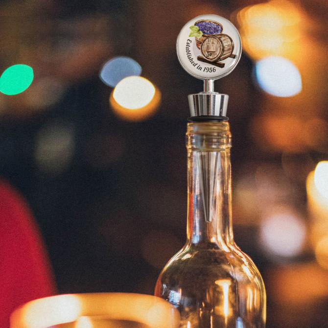 A drink bottle with a silver wine stopper featuring a logo design and a decorative top.