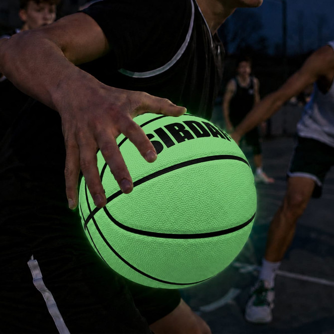 A glowing green basketball with a textured surface, held in a player's hand. The background features blurred players.