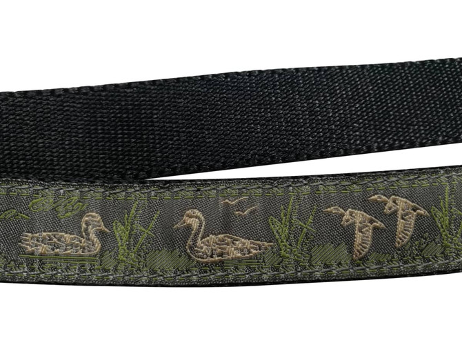 A detailed woven dog leash featuring a green and black design with duck motifs and grass accents.