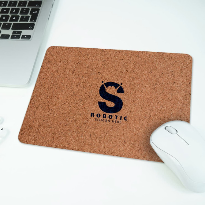 A cork mouse mat in a rectangular shape, featuring a dark logo, placed beside a white computer mouse and laptop.