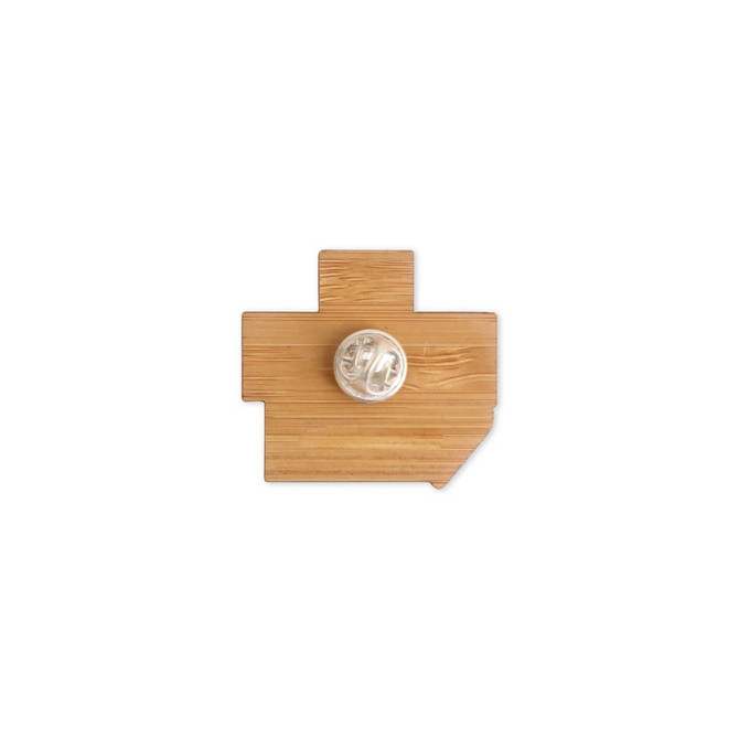 A custom-shaped bamboo lapel pin in a light brown colour, featuring a logo on the back.