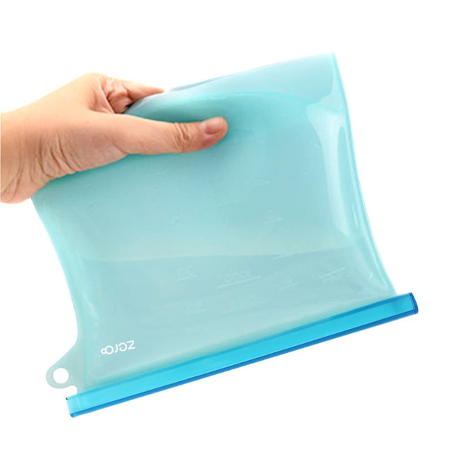 A silicone reusable storage pouch in light blue, held by a hand, featuring a transparent design and a blue base.