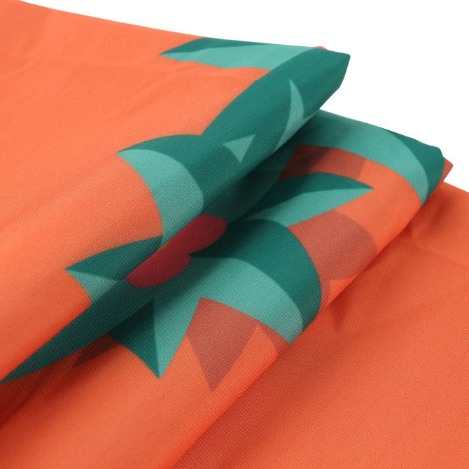An orange picnic blanket with green floral patterns, showcasing its folded design. It has a branding logo.