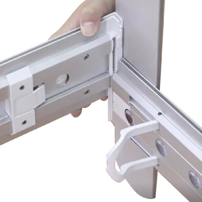 A close-up of a hand holding a metallic frame corner connector, featuring a clip mechanism in silver colour.