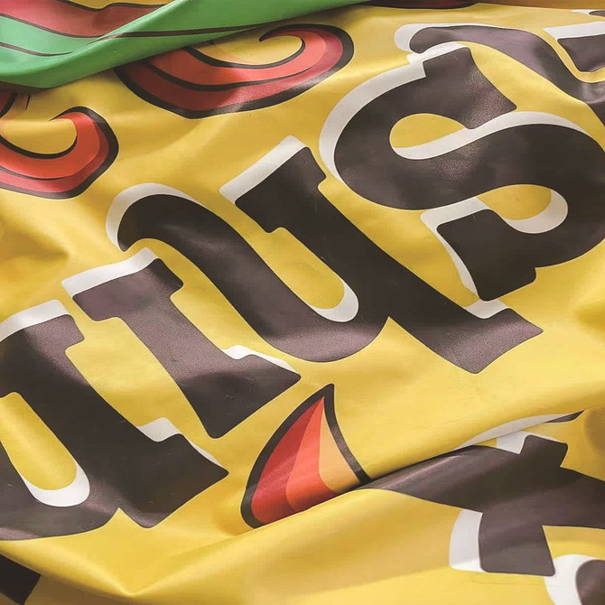 A vibrant yellow inflatable can with colourful graphics and a logo, featuring red and black elements.