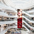 A hanging banner featuring a model with bold red lips and lipstick, displayed in a modern shopping centre.