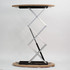 A portable display counter with a round wooden top and a silver folding support structure.