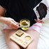 A clear glass mug filled with tea, on a wooden tray with a spoon and a snack, held by a person.