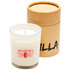 A white glass candle in a clear holder with a brown cylindrical box. The candle is labelled with a logo.