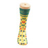 Bright yellow socks featuring a multicoloured leaf pattern, displayed on a sock model. Contains a logo.