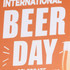 An orange rubber counter mat with a festive design, featuring graphics related to International Beer Day and a glass of beer.
