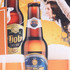 A rubber counter mat featuring two beer bottles with a vibrant orange background. The mat includes a logo.