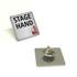 A silver lapel pin featuring the text "STAGE HAND" and a logo, with a metal clasp on the back.