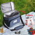 A blue cooler bag with a grey interior, capable of holding 16 cans, has a logo on the front.