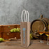 A jute wine carrier in natural brown with white handles, surrounded by grapes and wine glasses.