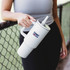 A drink bottle in white with a handle and a straw, featuring a logo on the front.