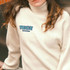 A light cream turtleneck sweater featuring a colourful embroidered patch with the word "PEACE."