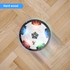 A hover soccer ball with a black and white design, featuring coloured lights, on a hardwood floor.