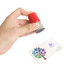 A round stamp with a red top and grey base held above a business card featuring a colourful tree design.