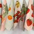 Custom cotton tea towels in various pastel colours featuring illustrations of fruits and vegetables.