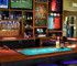 A bar mat featuring a tropical design in vibrant colours, laid out on a bar with drinks nearby.