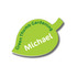 A green leaf-shaped badge featuring text and a logo, with a glossy finish.